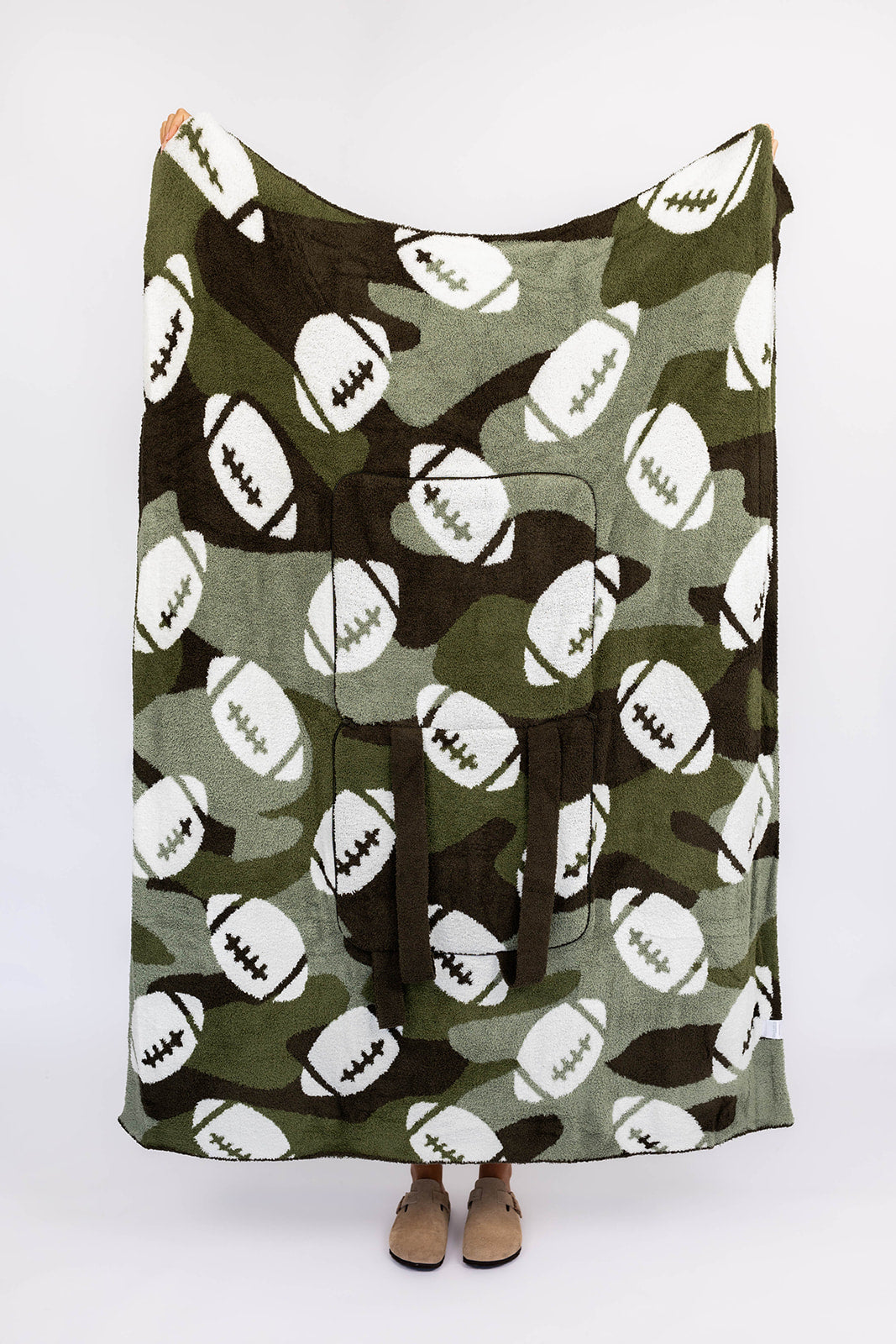Person holding a green camouflage blanket with football pattern on a white background