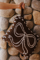 Bow quillow folded into a pillow and held by its wrist strap.