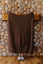 Brown waffle quillow opened into a blanket, showing its storage pocket.