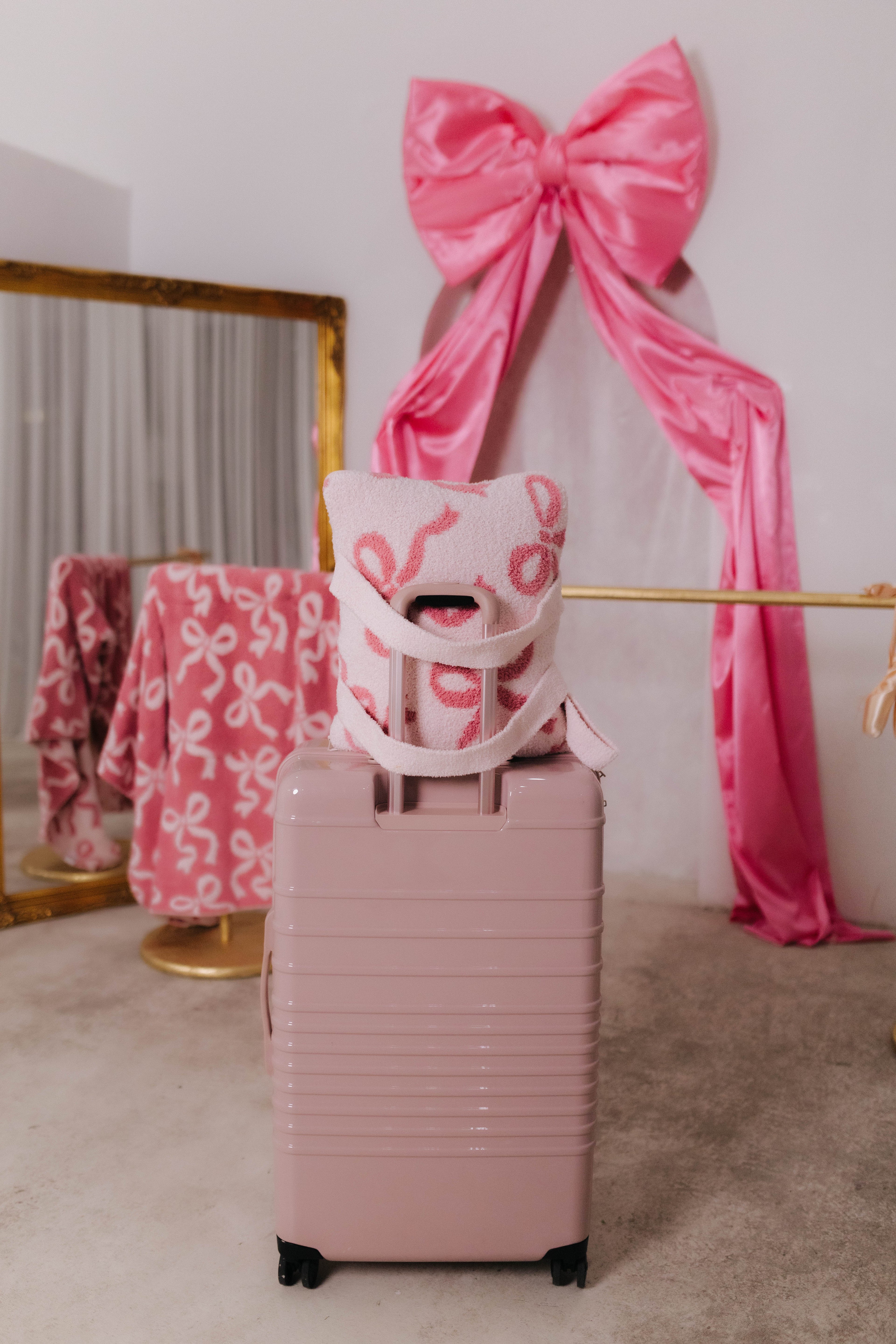 Pink suitcase with a pink bow and decorative quillow in a room setting