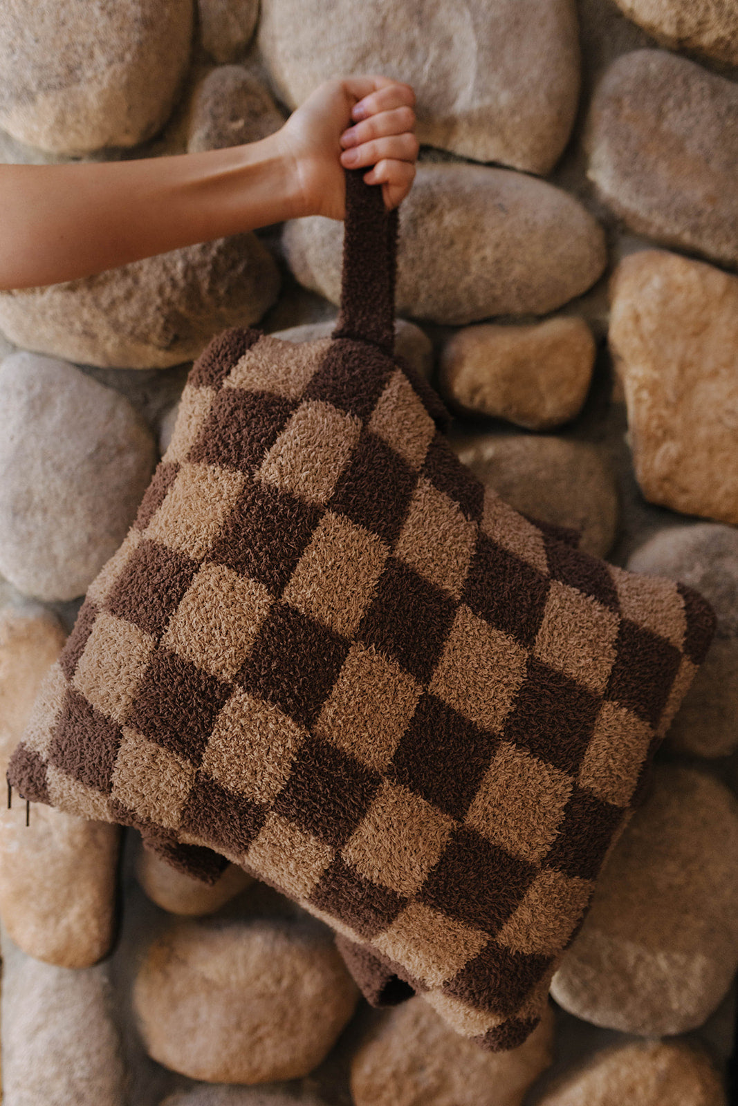 Brown check quillow folded into a pillow with a wrist strap.
