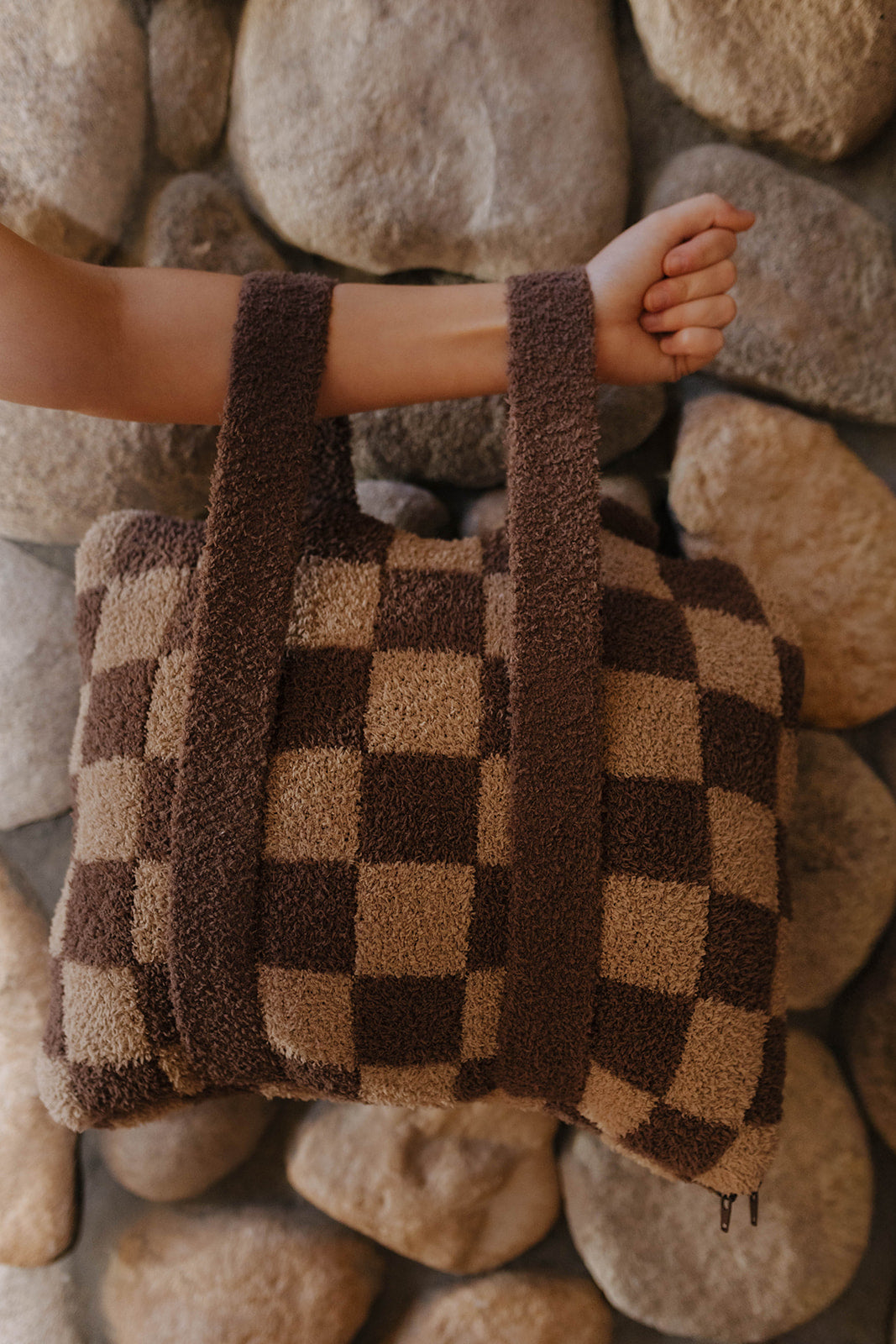 Brown check quillow folded with both backpack straps visible.