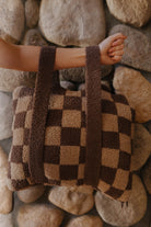 Brown check quillow folded with both backpack straps visible.