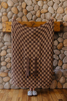 Tonal brown check quillow opened into a blanket with the pocket and straps visible.