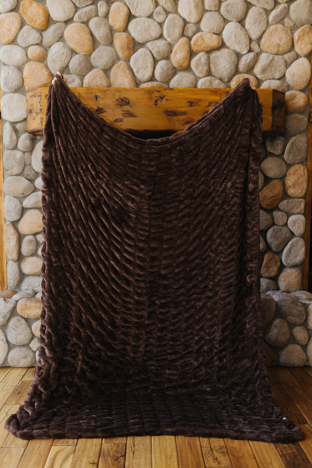 Brown faux fur blanket held open to show its plush ridged texture.