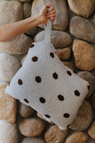 Blue and brown polka dot quillow folded and held by its wrist strap.