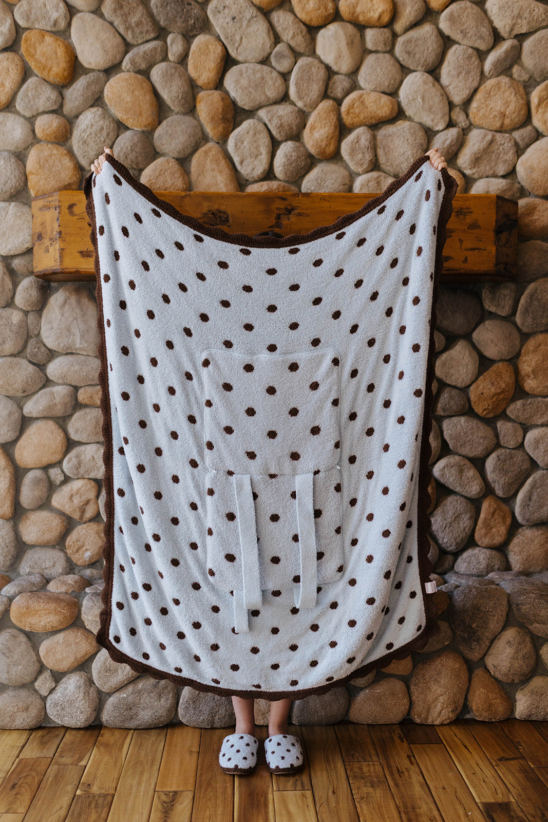 Light blue quillow with brown polka dots and scalloped edges held open.
