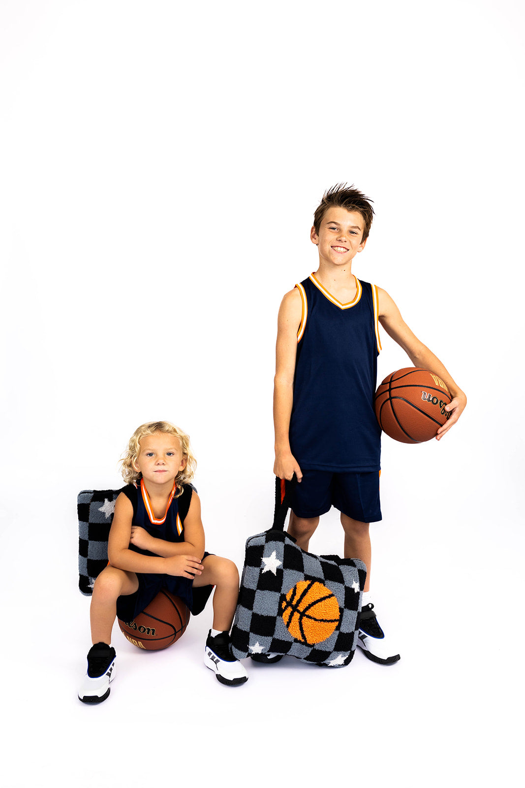 Two children with basketballs and quillows on a white background