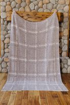 Reverse of the plaid blanket held open by a stone fireplace.
