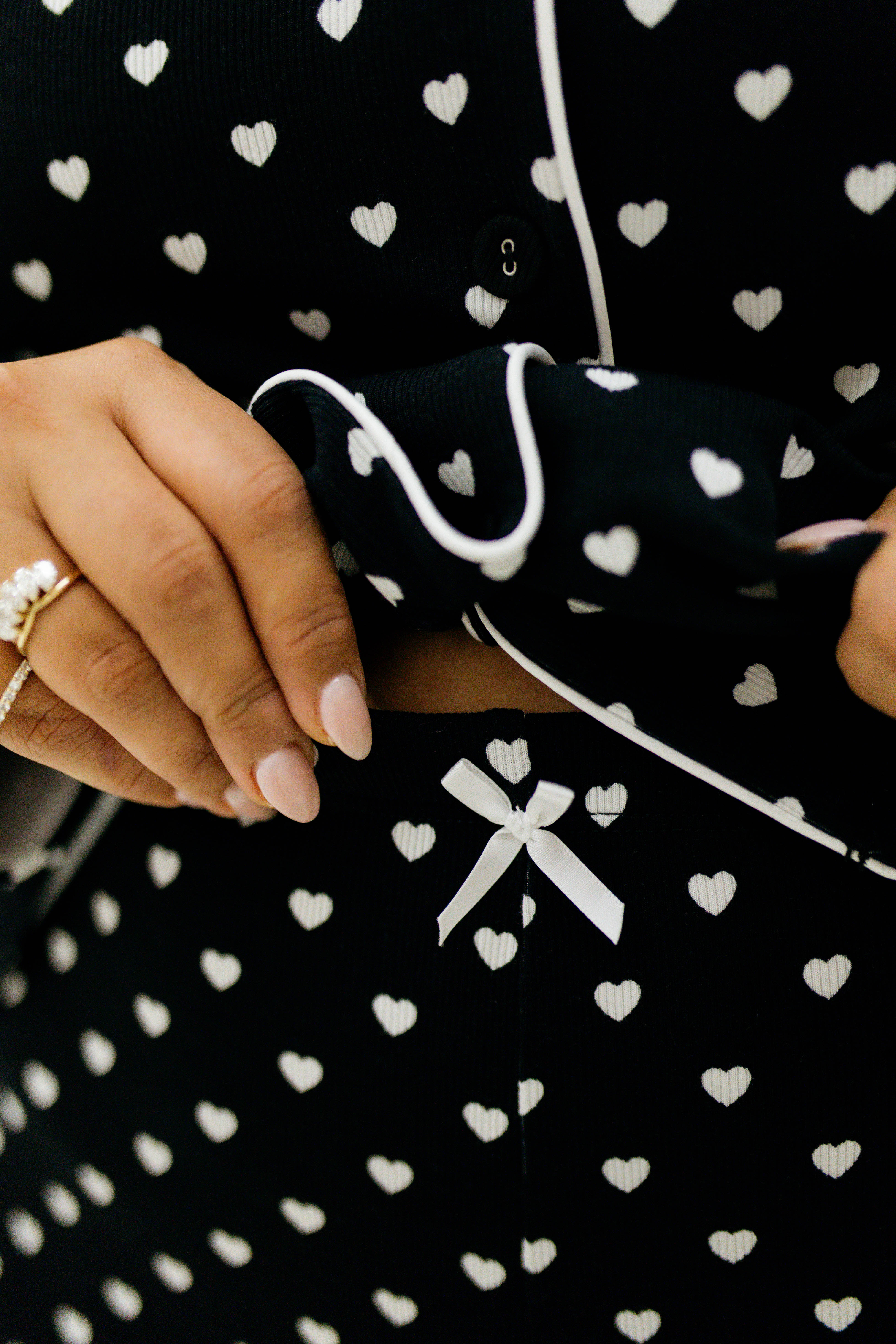 Black fabric with white heart patterns and a white ribbon design.
