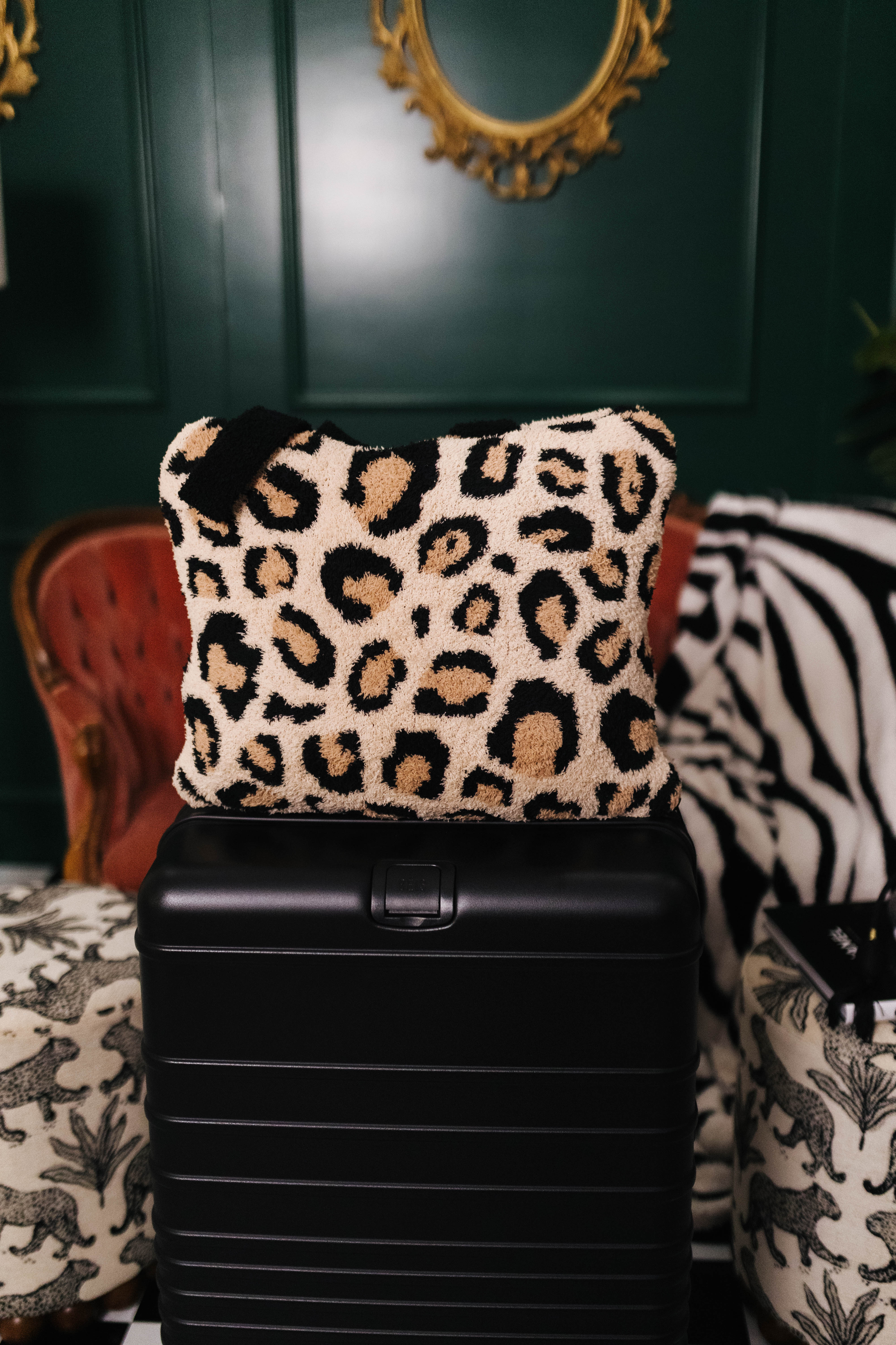 Leopard print quillow on a black suitcase with a decorative background