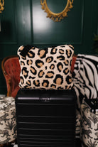 Leopard print quillow on a black suitcase with a decorative background