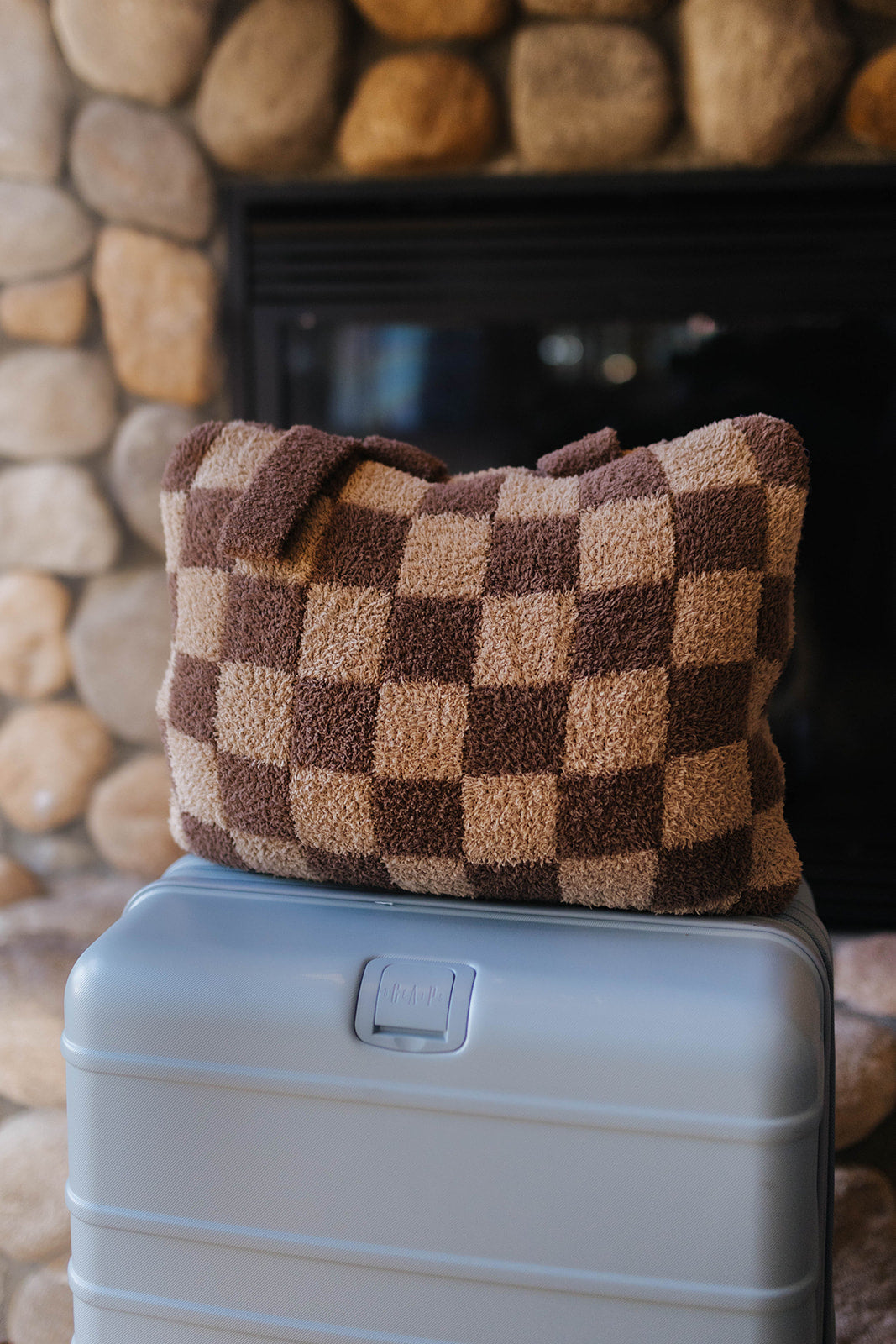 Folded brown check quillow resting on a suitcase.