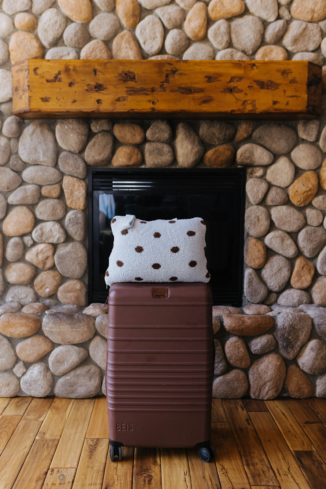 Folded blue and brown polka dot quillow on a suitcase.