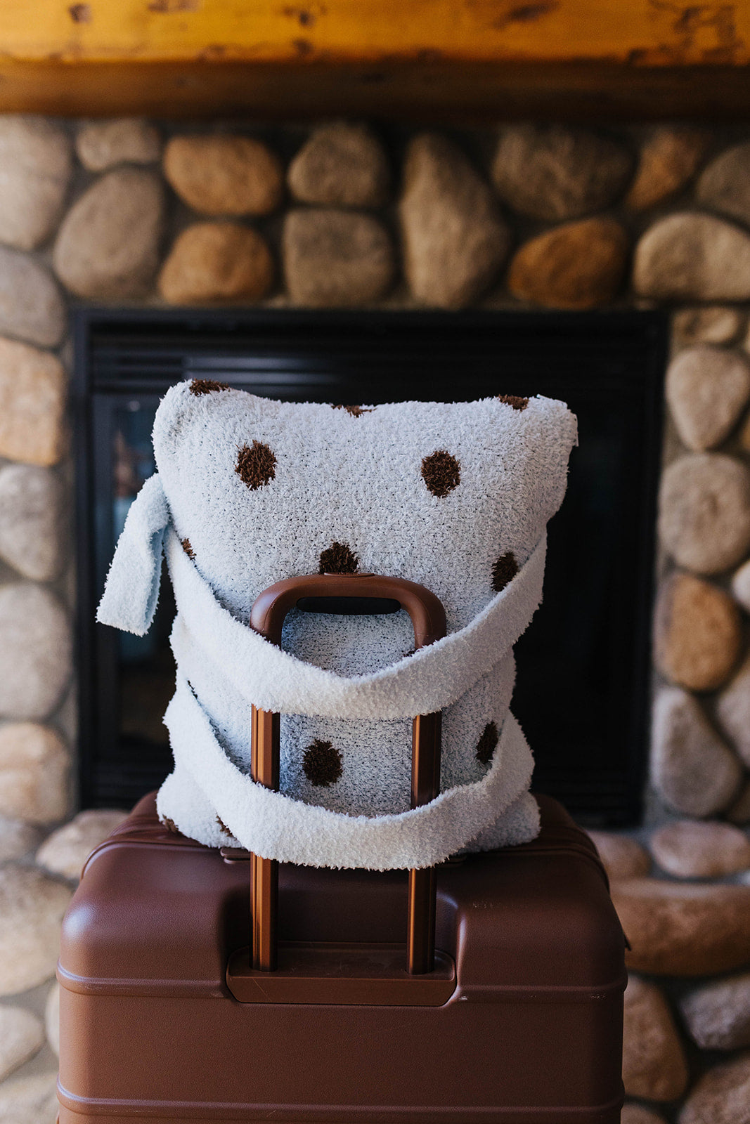 Polka dot quillow folded with backpack straps on a suitcase.