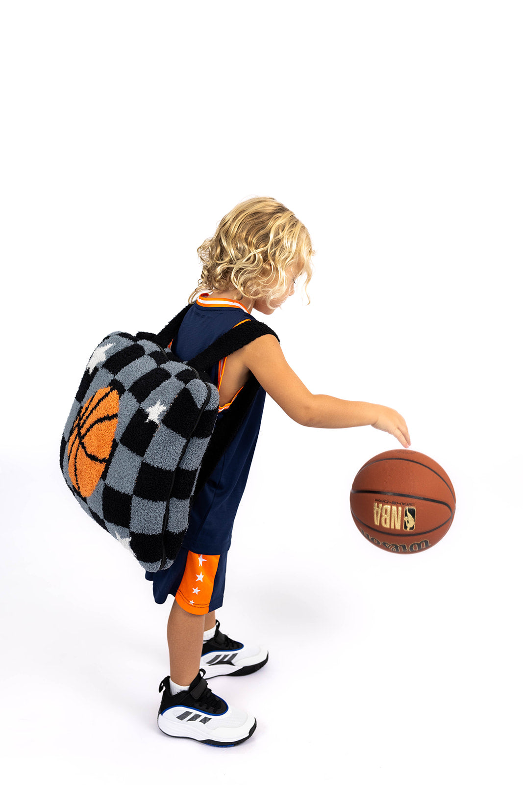 Child with a checkered basketball backpack quillow and basketball on a white background