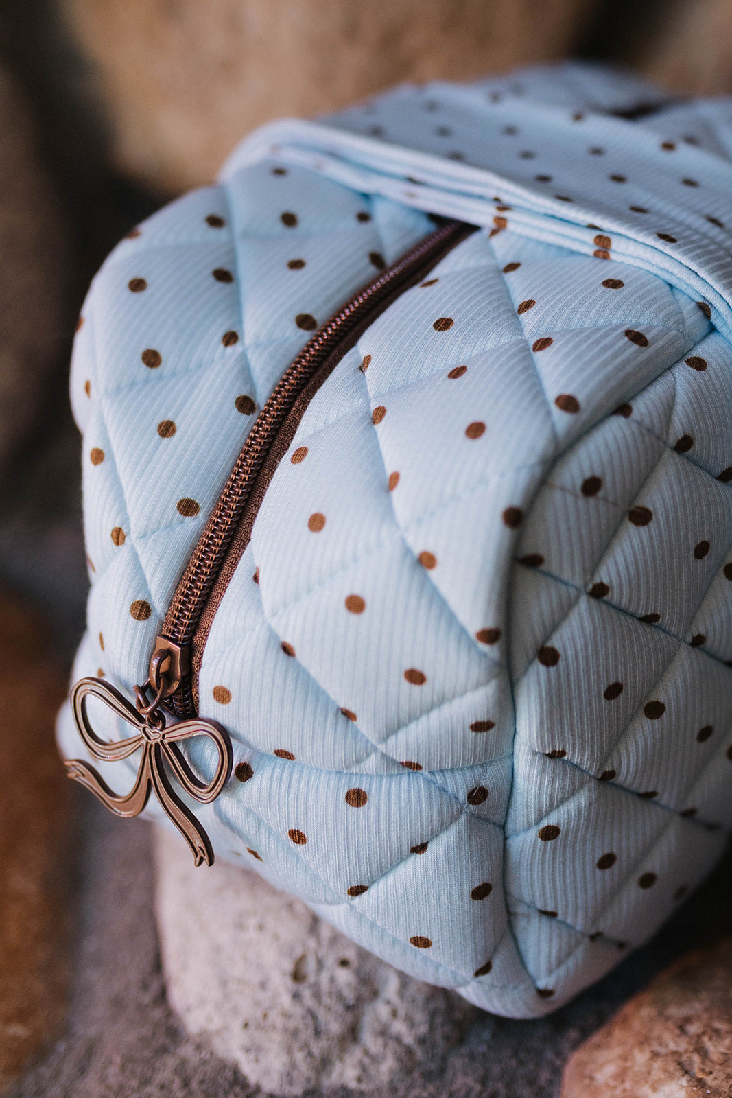 Close view of the quilted blue and brown polka dot cosmetic bag and zipper.
