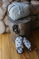 Blue polka dot cosmetic bag and matching slippers on a wood stool.
