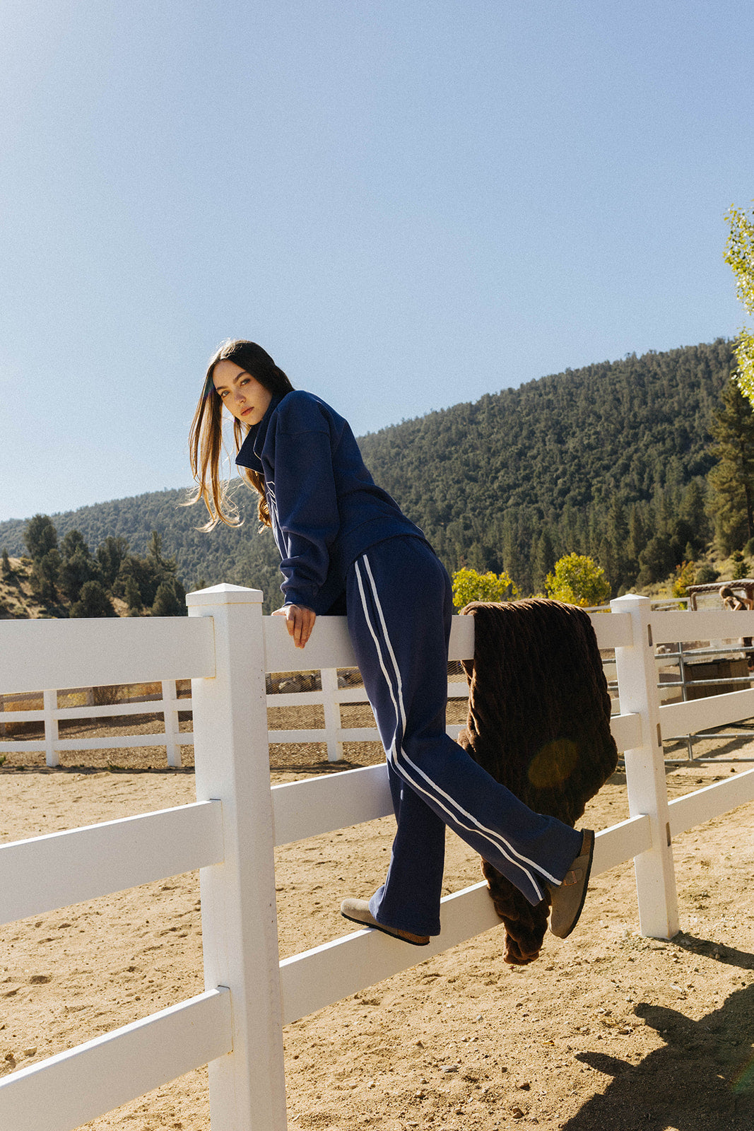 Full length side view of the blue Homebody sweatshirt and sweatpants with contrasting stripes.