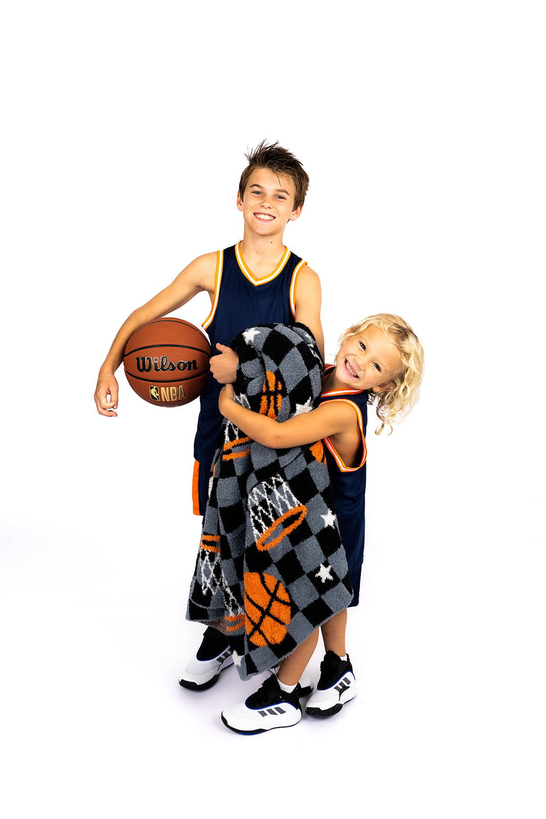 Two children in basketball-themed outfits with a blanket, on a white background