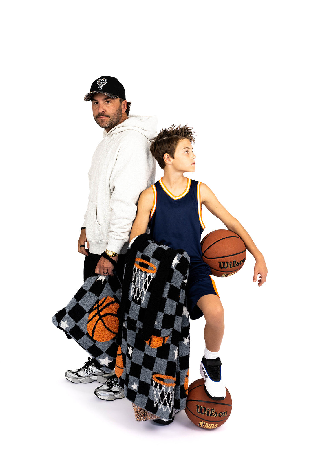 Man and child with basketballs and a checkered basketball blanket on a white background