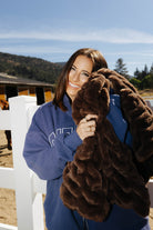 Close view of a model holding the chocolate brown faux fur kid blanket against their face.