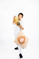 Child holding a baseball glove and a quillow with a baseball design on a white background
