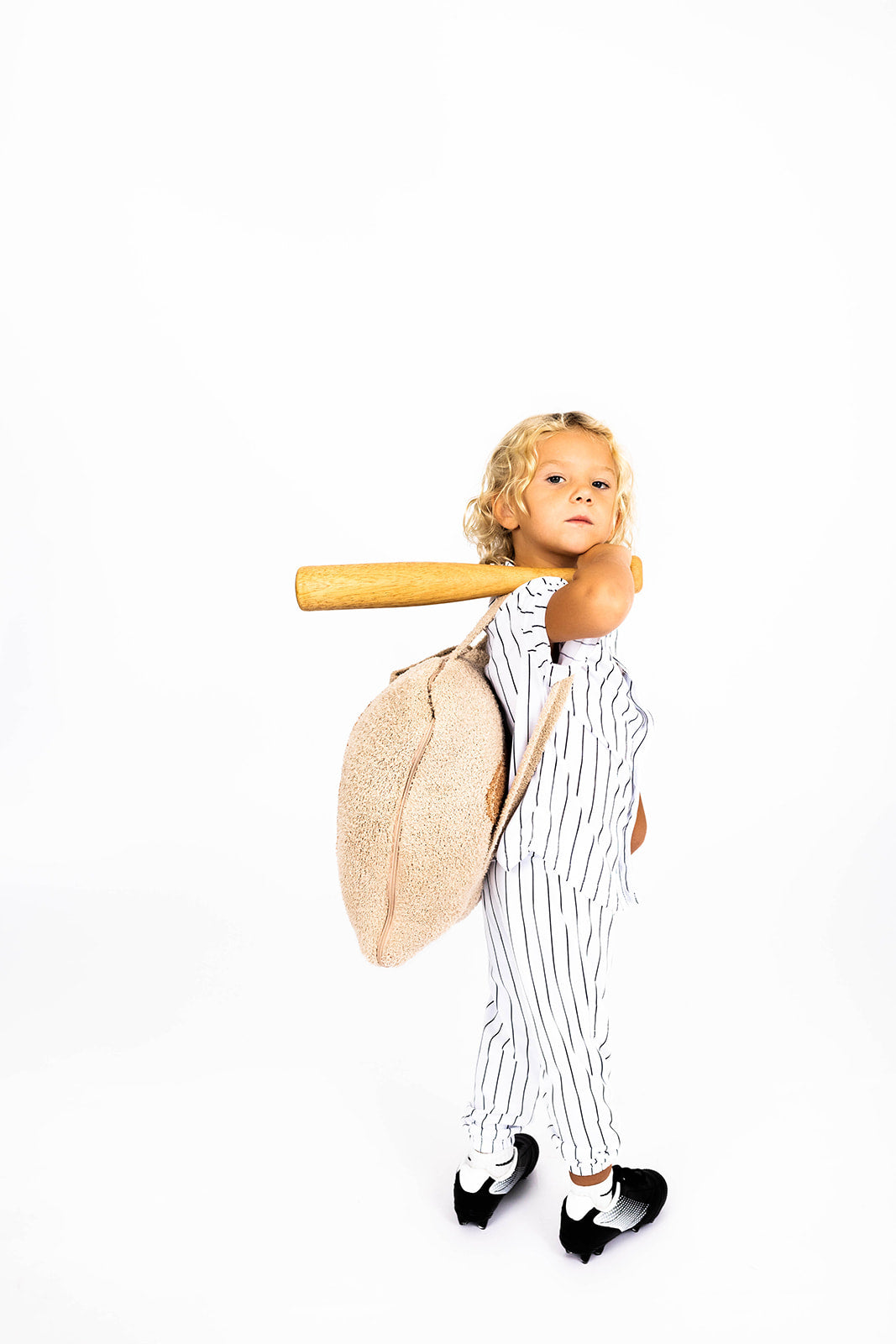 Child in pinstripe suit holding a baseball bat and glove and quillow on a white background