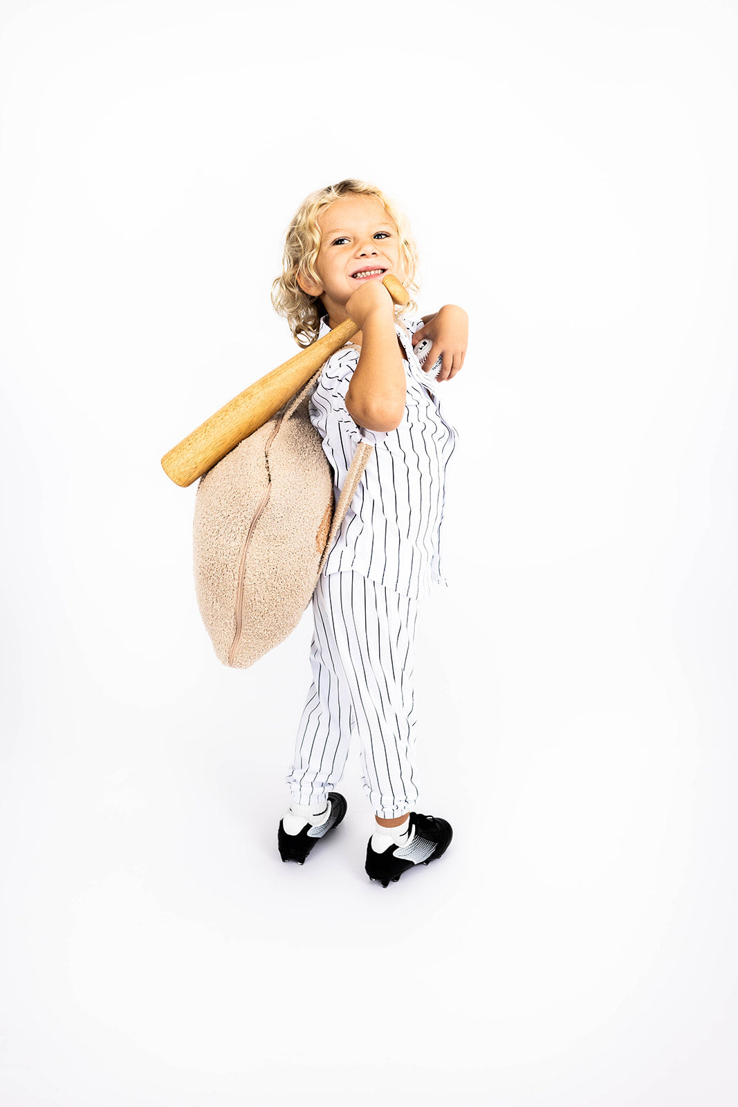 Child in pinstripe outfit holding a baseball bat and glove on a white background