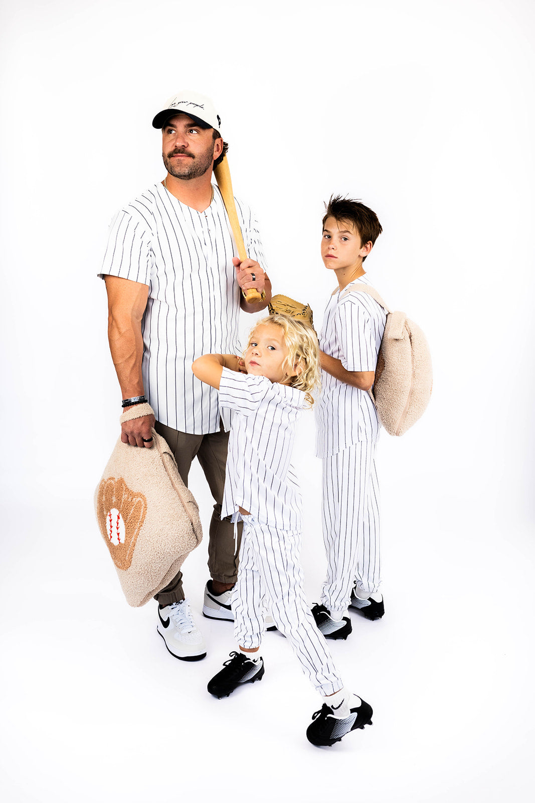 Family of three in vintage baseball uniforms posing together on a white background