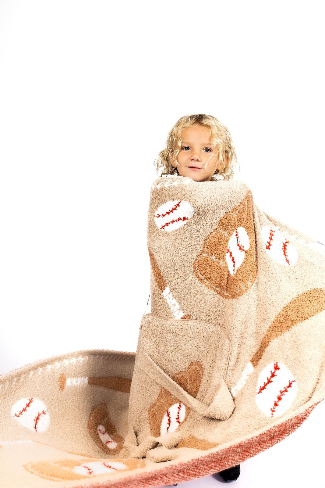 Child wrapped in a baseball-themed blanket on a white background