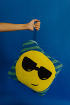 holding the quillow by the wristlet strap against a solid blue background