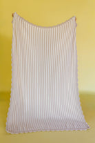 Pinstripe blanket with scallop detailing on a yellow background