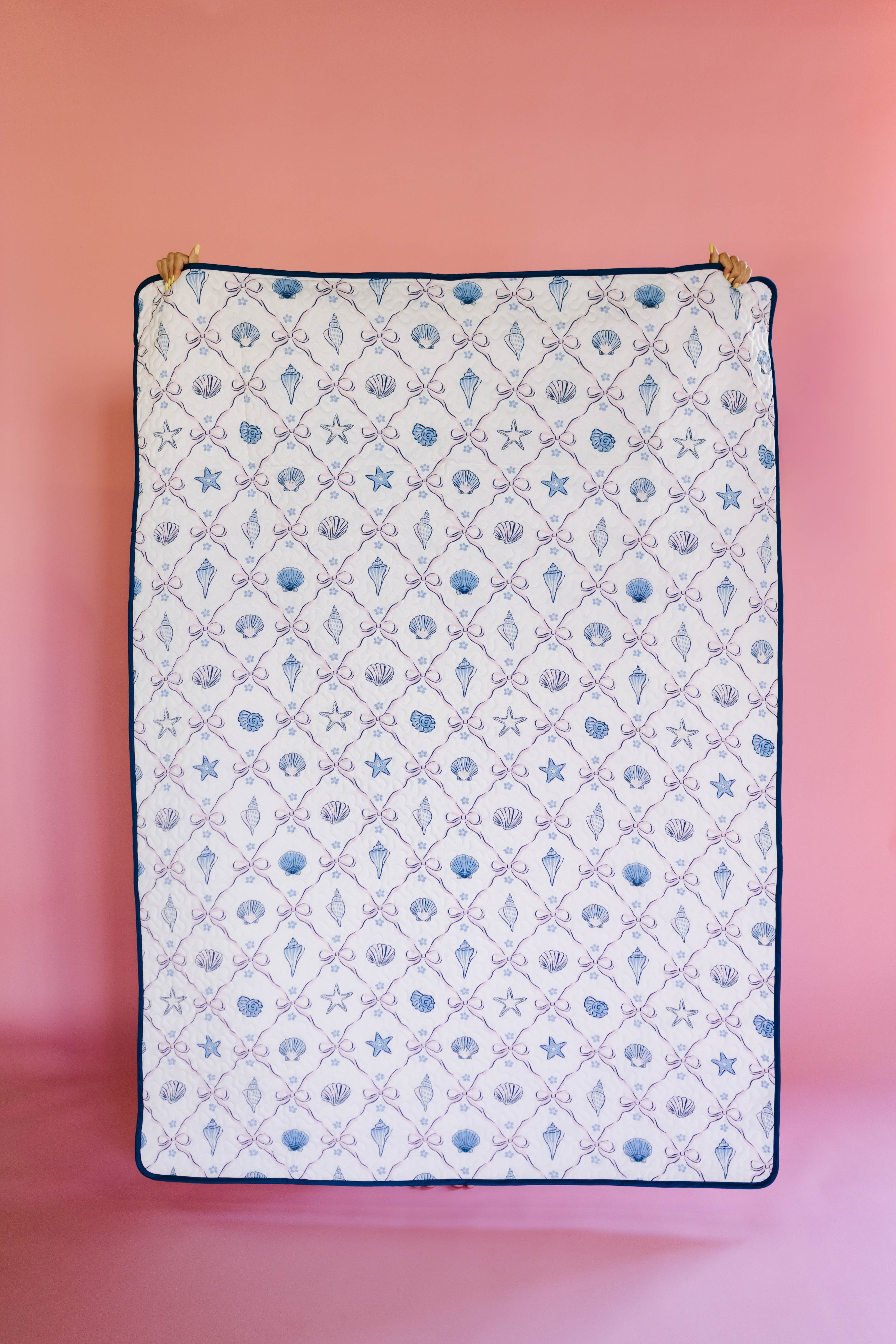 Patterned outdoor quillow/blanket with sea-themed design on a pink background