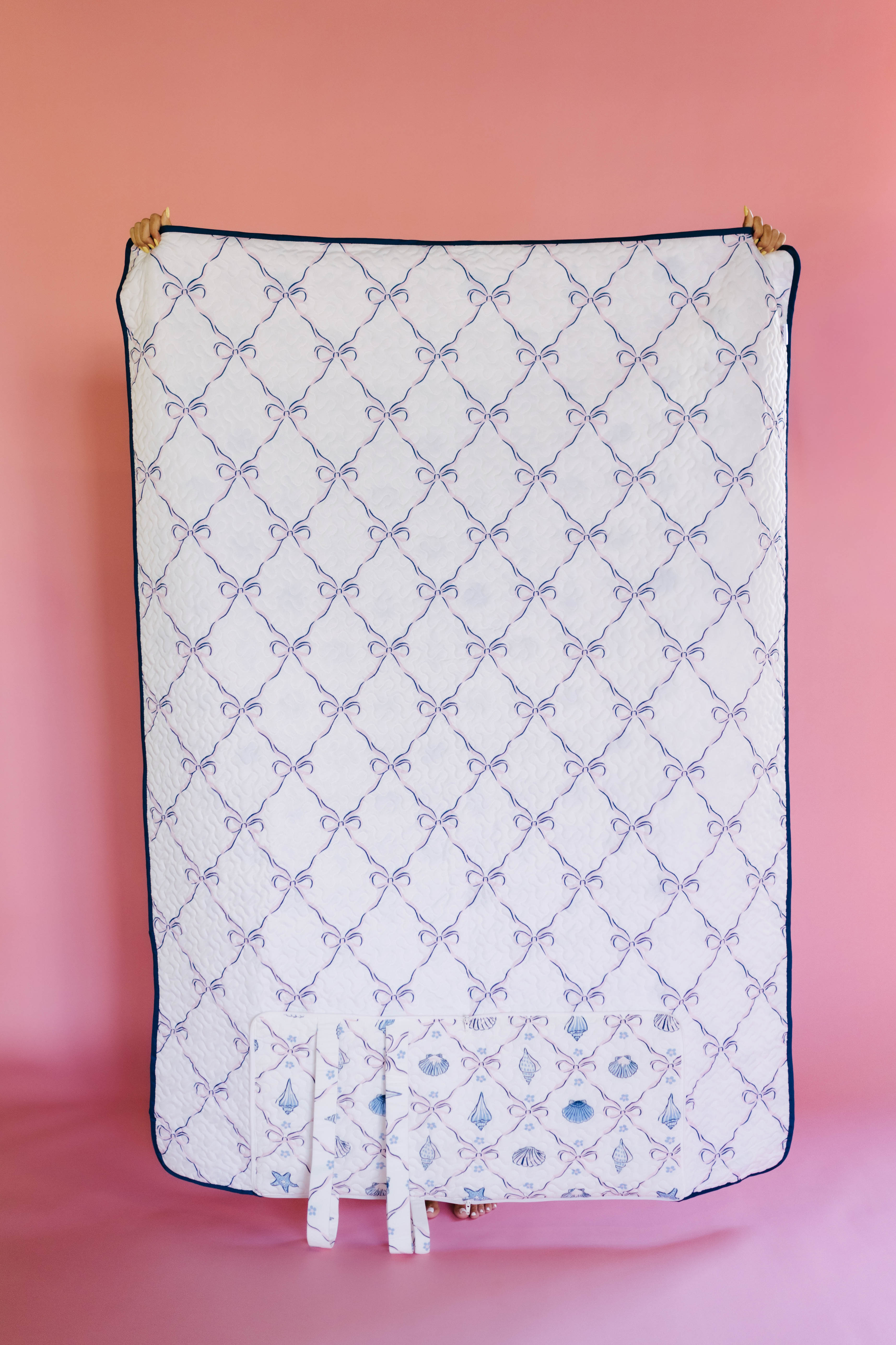 Waterproof side of outfoot quillow with bow pattern on a pink background