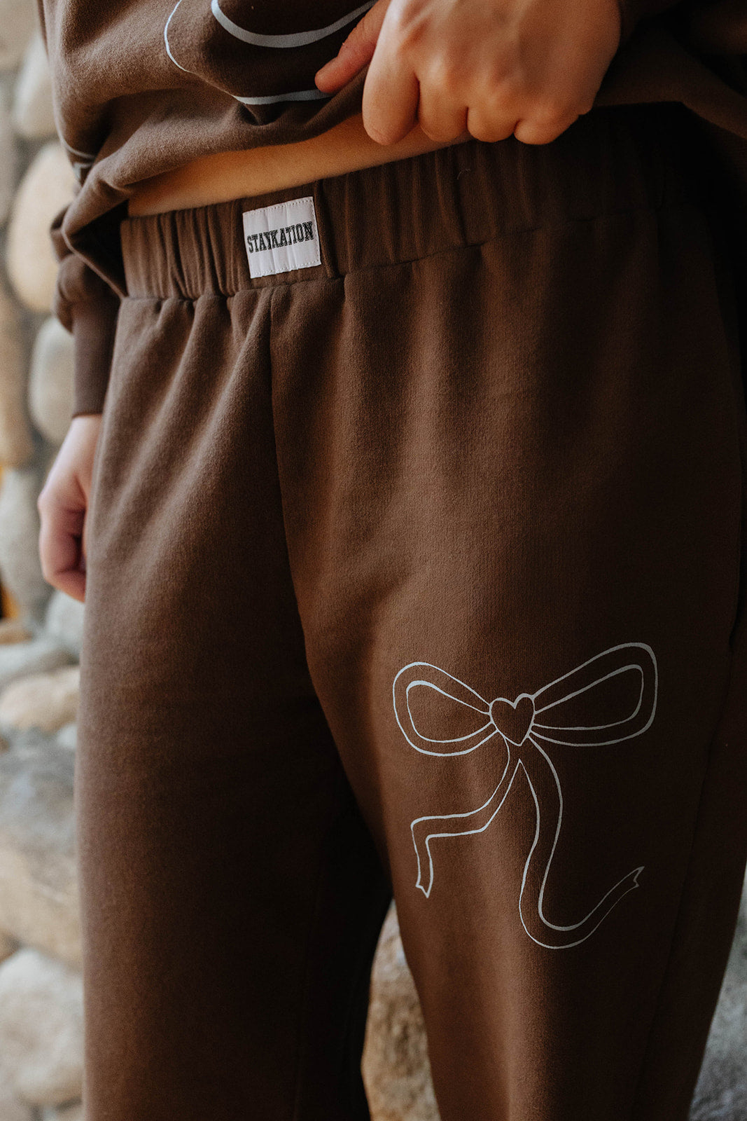 Close view of the brown bow sweatpants and side graphic.