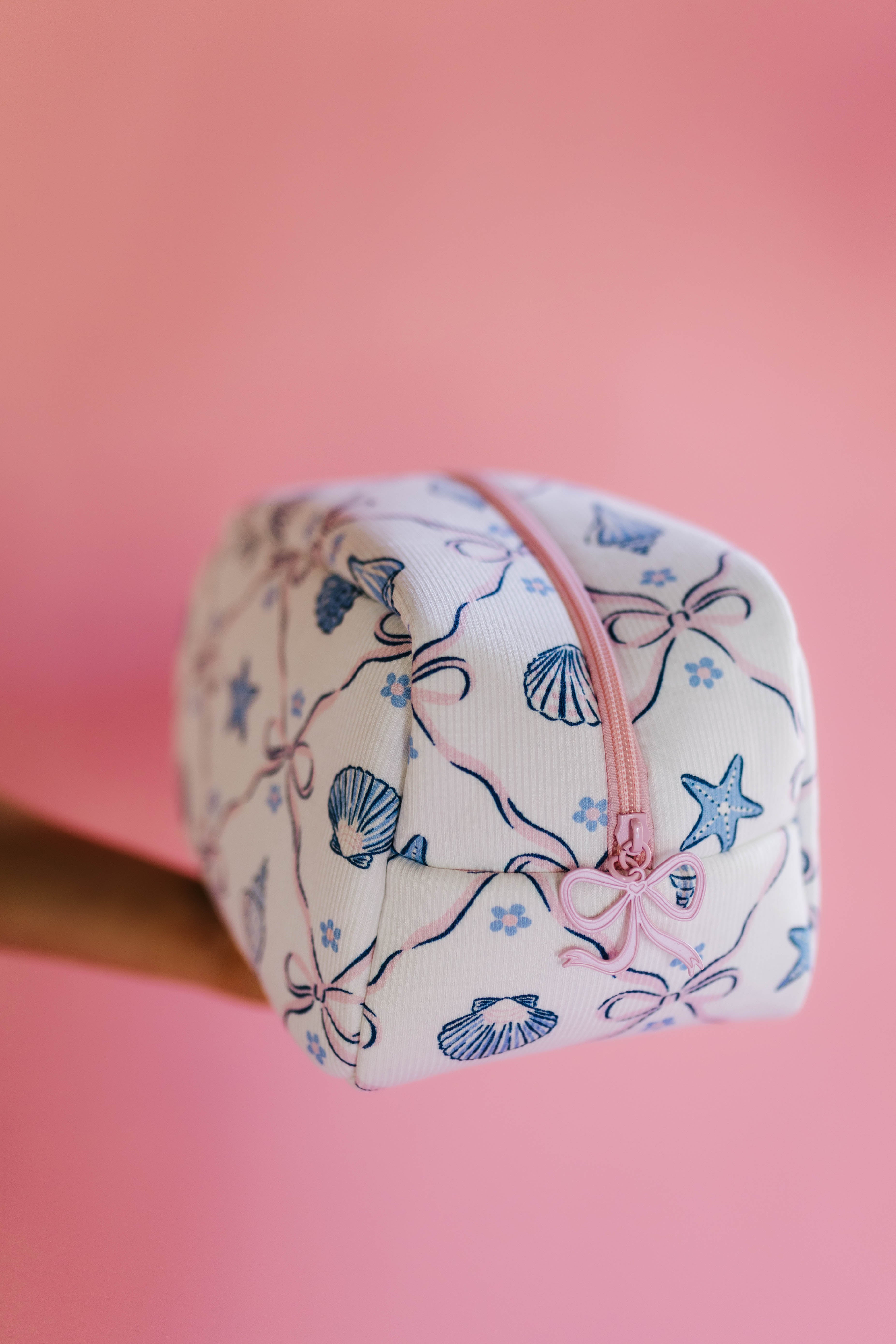 cosmetic bag with shell design on a pink background