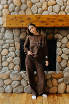 Full length front view of the brown sweatshirt and sweatpants with blue outlined bows.