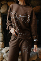Front view of the brown sweatshirt with a large outlined bow graphic.