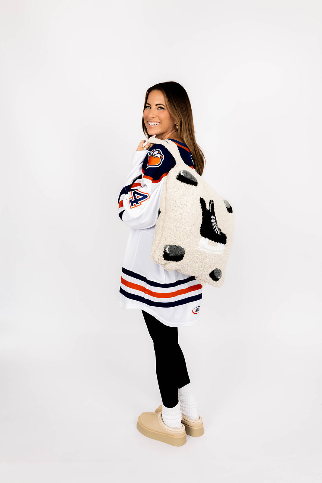 Woman wearing a sports jersey and holding hockey quillow on a white background