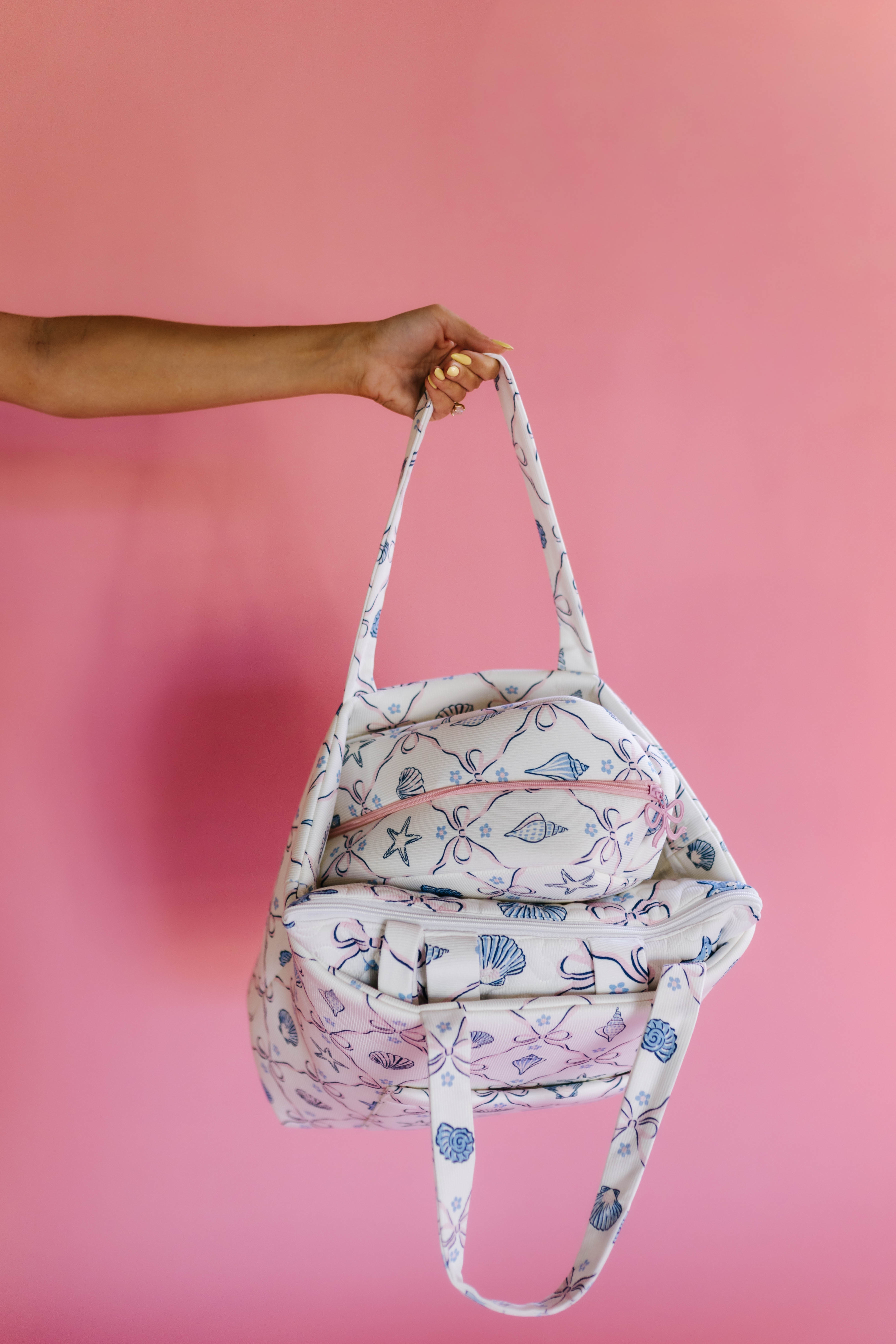 Person holding a patterned bag against a pink background