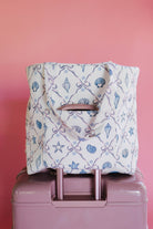 Tote bag with shell pattern on a pink suitcase against a pink background