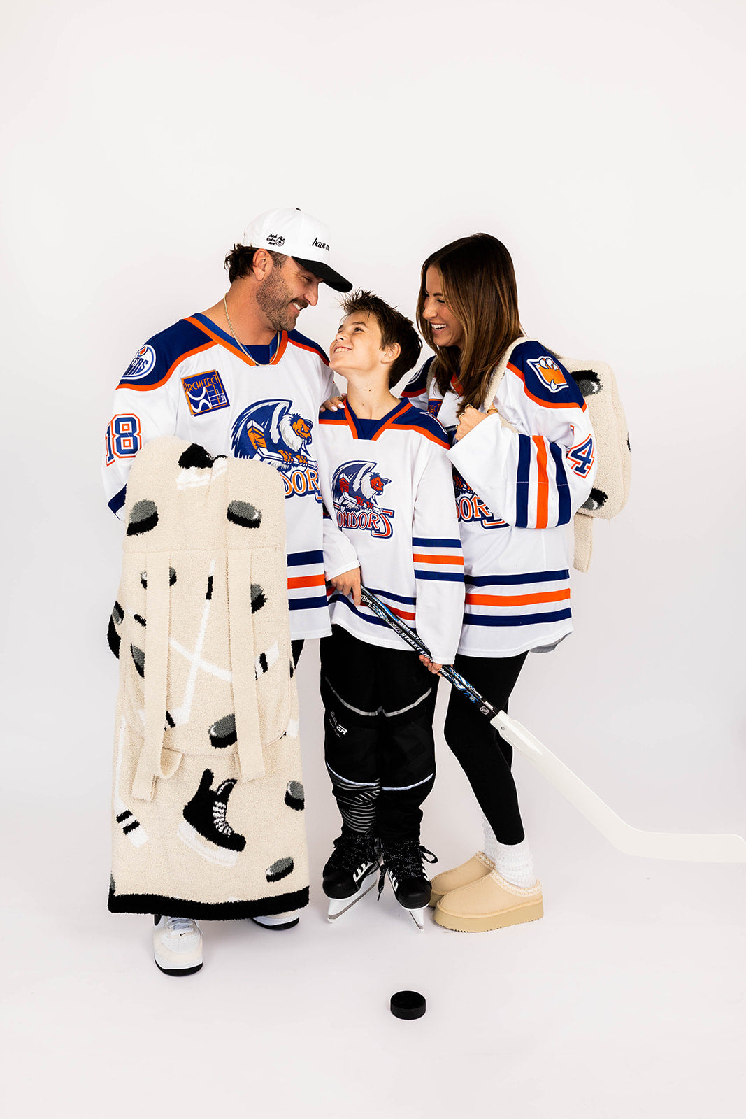 Family wearing hockey-themed jerseys and hockey quillow with a white background