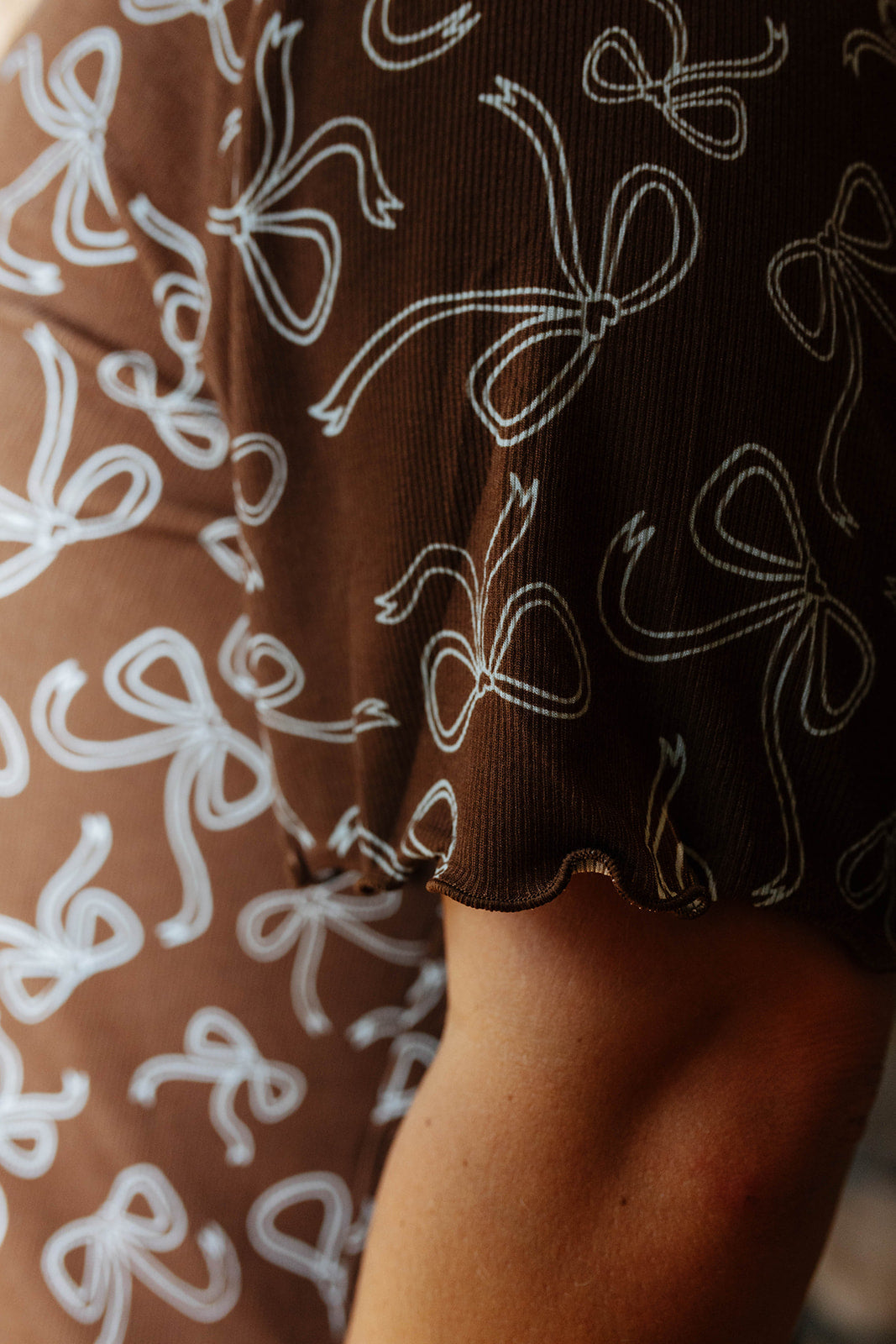 Close view of the scalloped sleeve edge on the brown bow print pajama top.