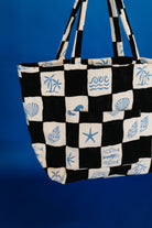 Black and white checkered tote bag with blue sea-themed patterns on a blue background