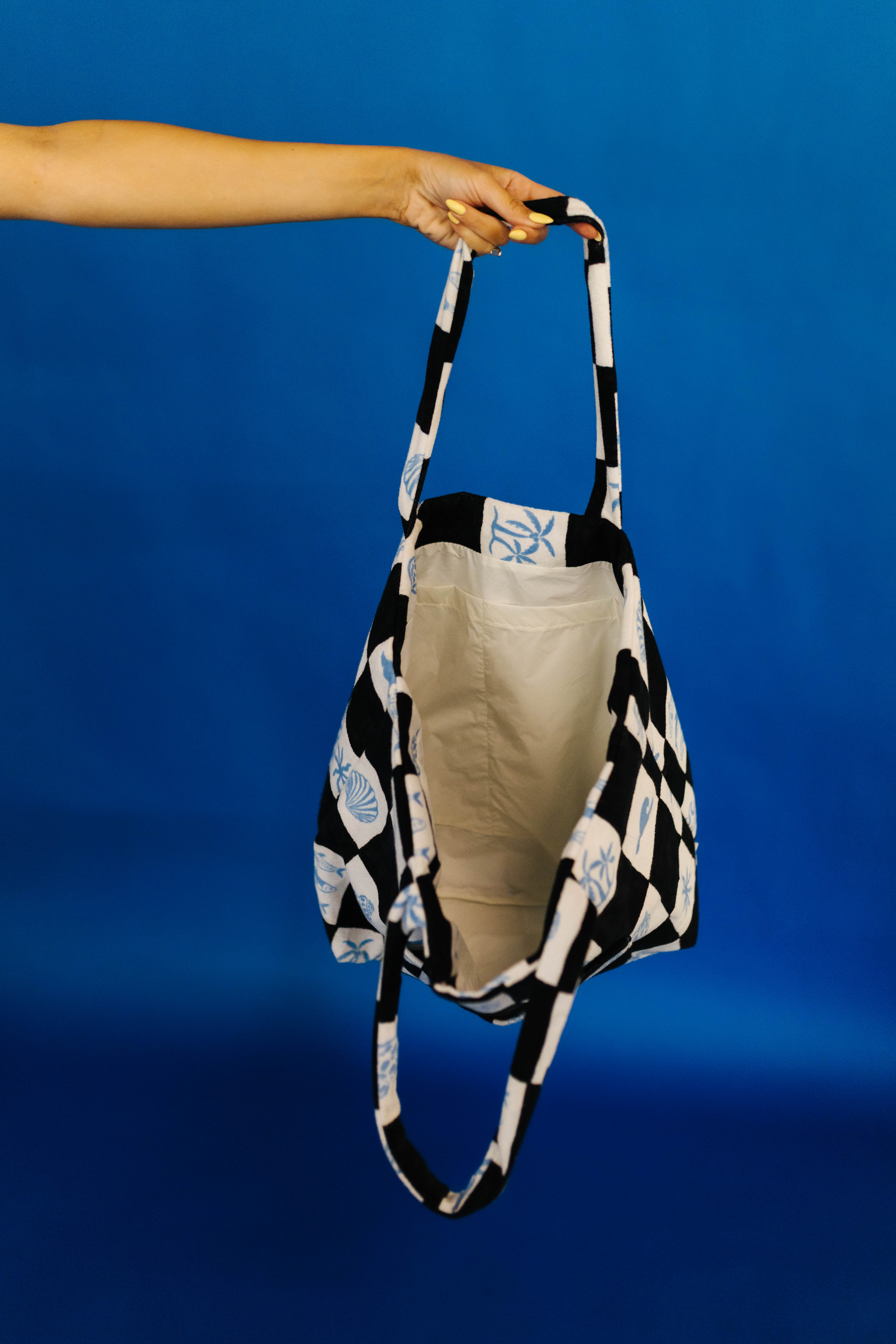 Person holding a black and white checkered bag against a blue background