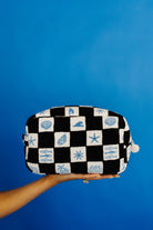 Checkered cosmetic bag with sea-themed patterns held against a blue background