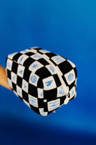 Black and white checkered cosmetic bag with blue sea-themed designs on a blue background