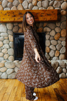 Model holding out the hem of the brown bow print robe to show its drape.