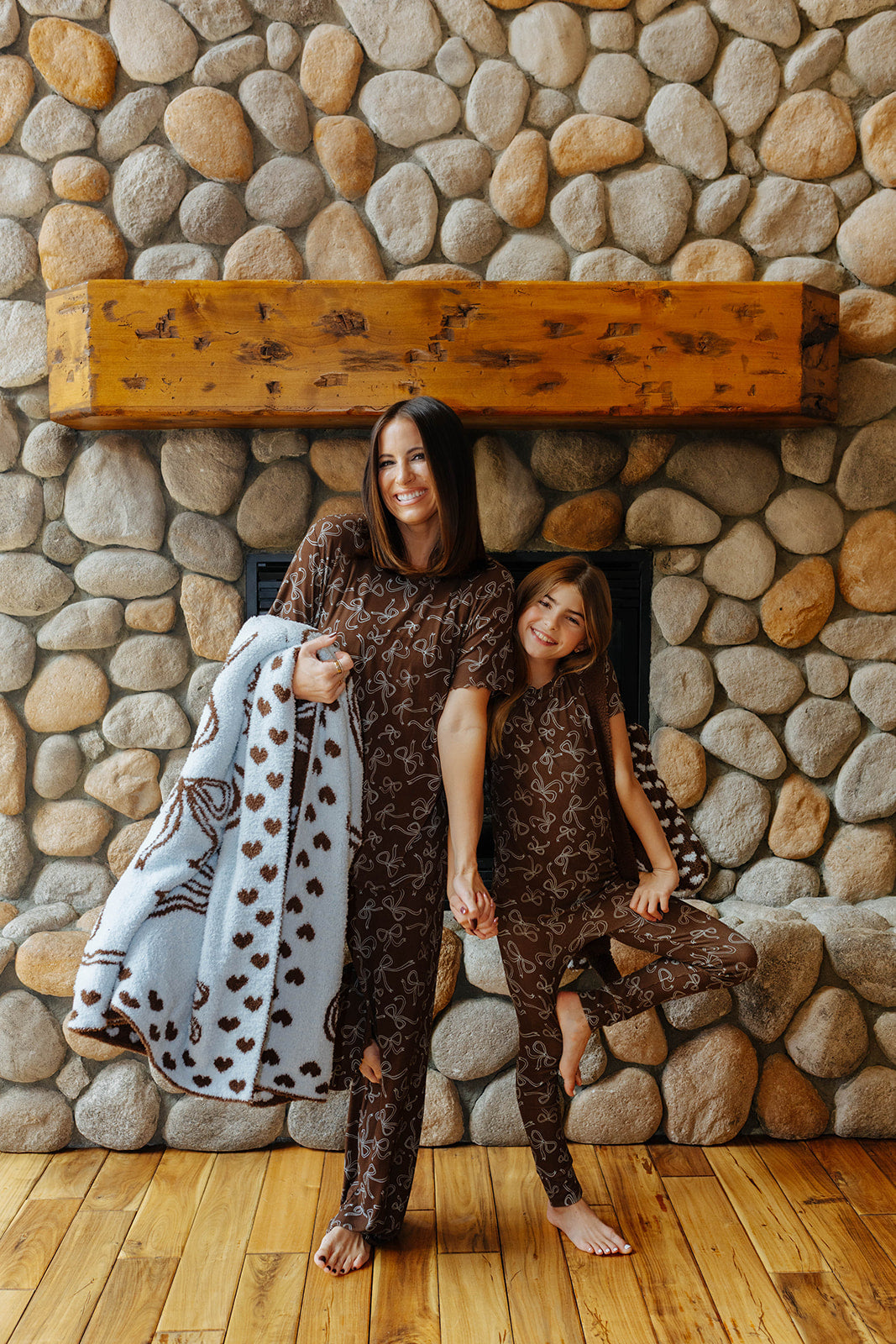 Model holding the light blue quillow with brown bow print beside a child.